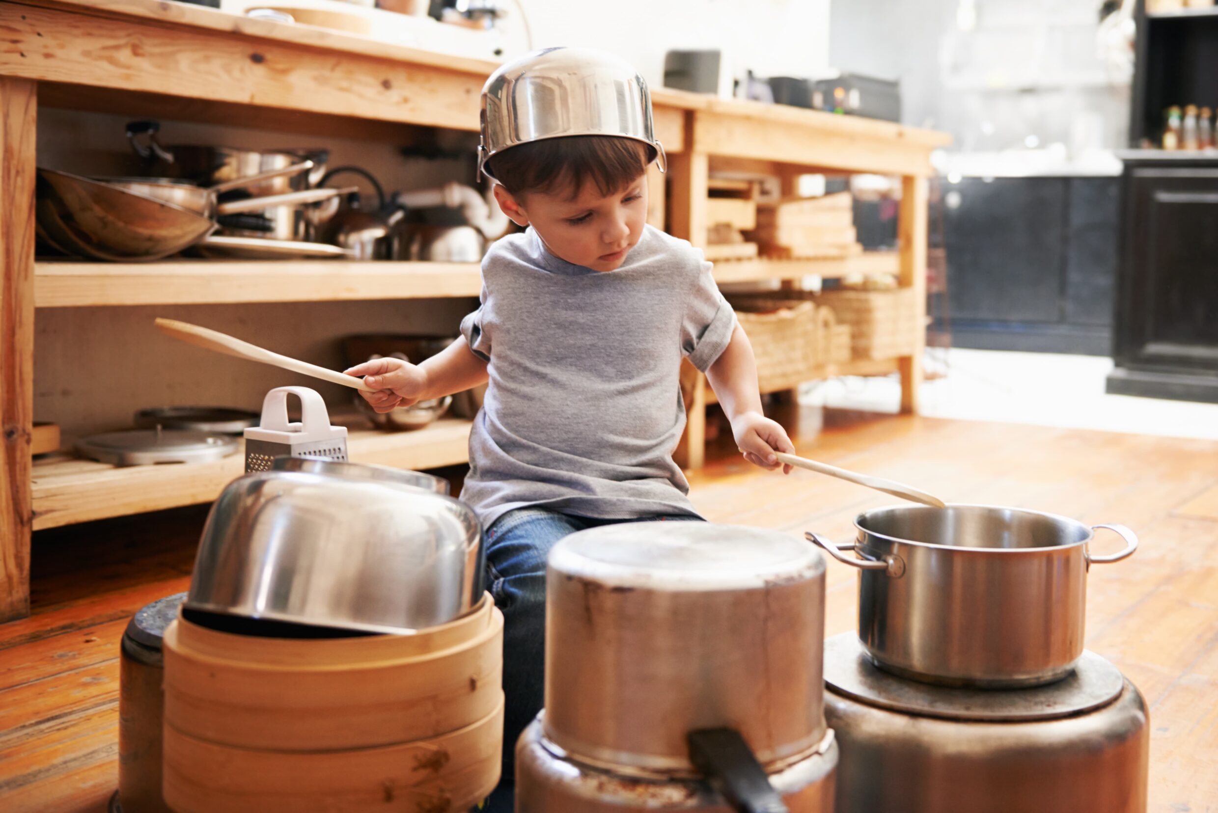 small boy on the floor playing pots and pans like drums