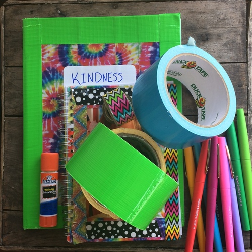 Decorated composition notebook with rolls of duct tape and colorful ink pens