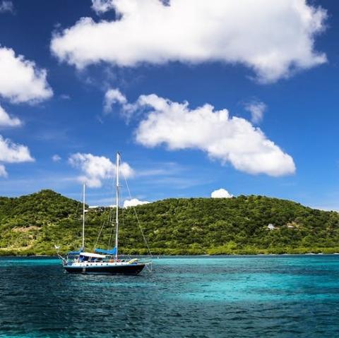 a boat on crystal blue water in front of a green island