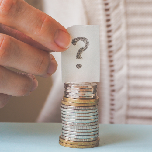 A hand holding a drawn question mark above a stack of coins